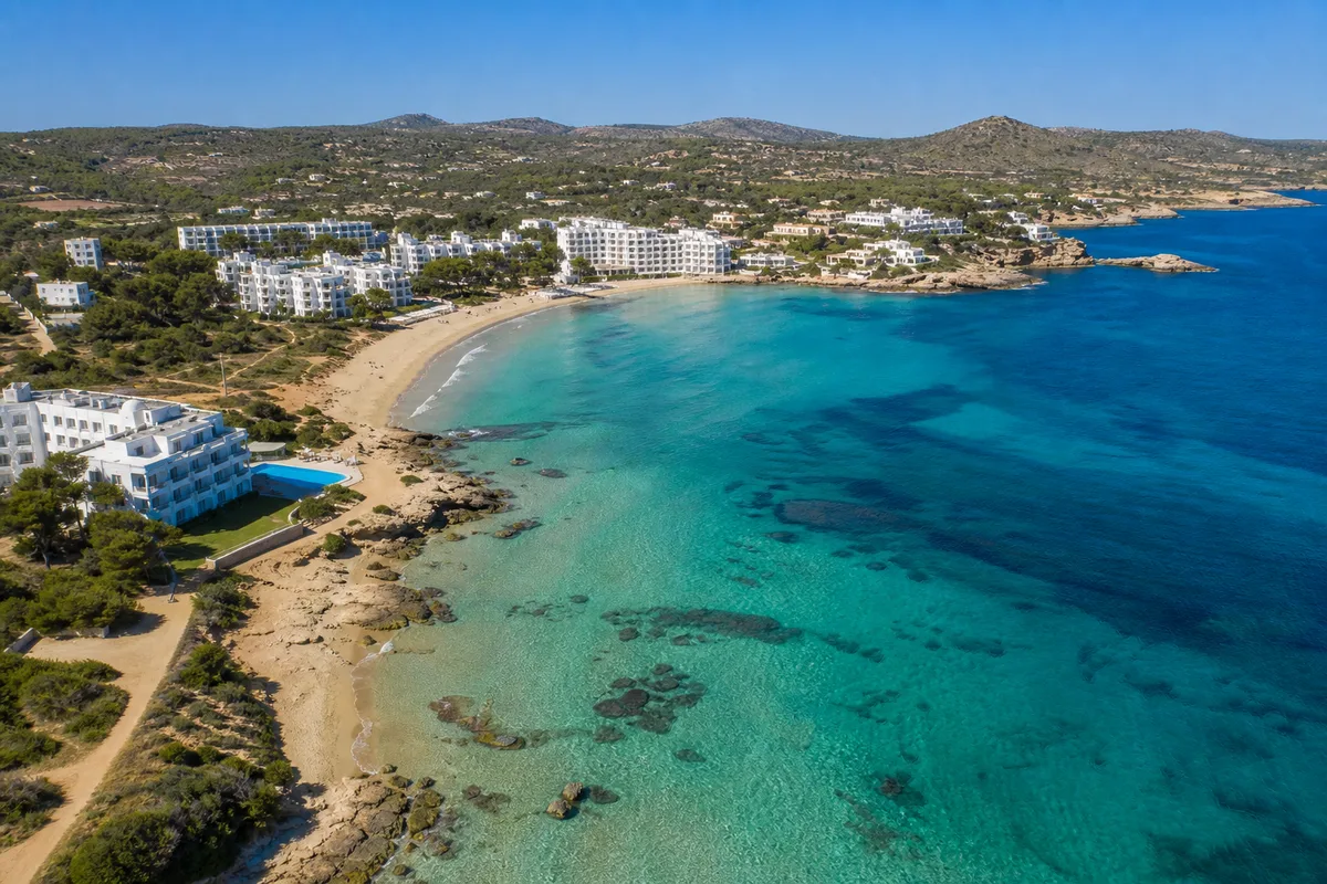 Vue aérienne d’une plage de sable et d’une baie méditerranéenne bordée d’hôtels blancs
